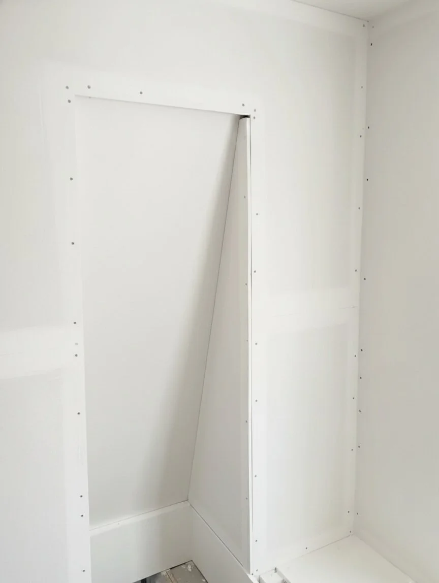 Completed white drywall (gipsosanida) installation in residential attic, showing smooth, finished corner.