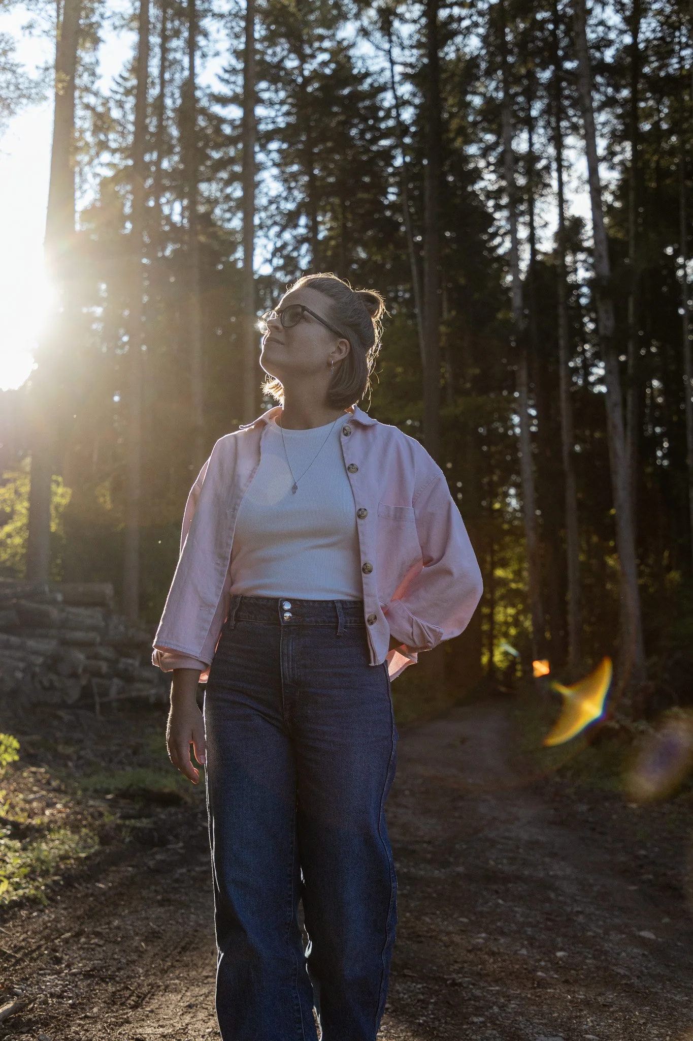 Kristina Lehmann steht im Wald, Sonnenlicht strahlt durch die Bäume im Hintergrund.