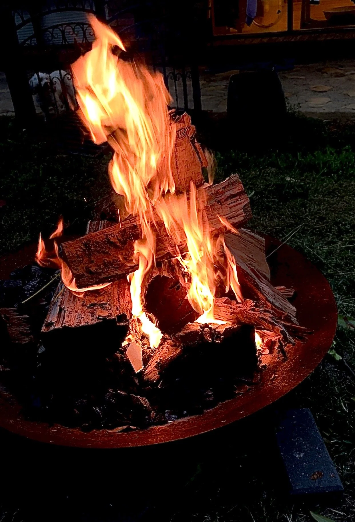 A bonfire with burning logs in a fire pit in an outdoor setting at night.