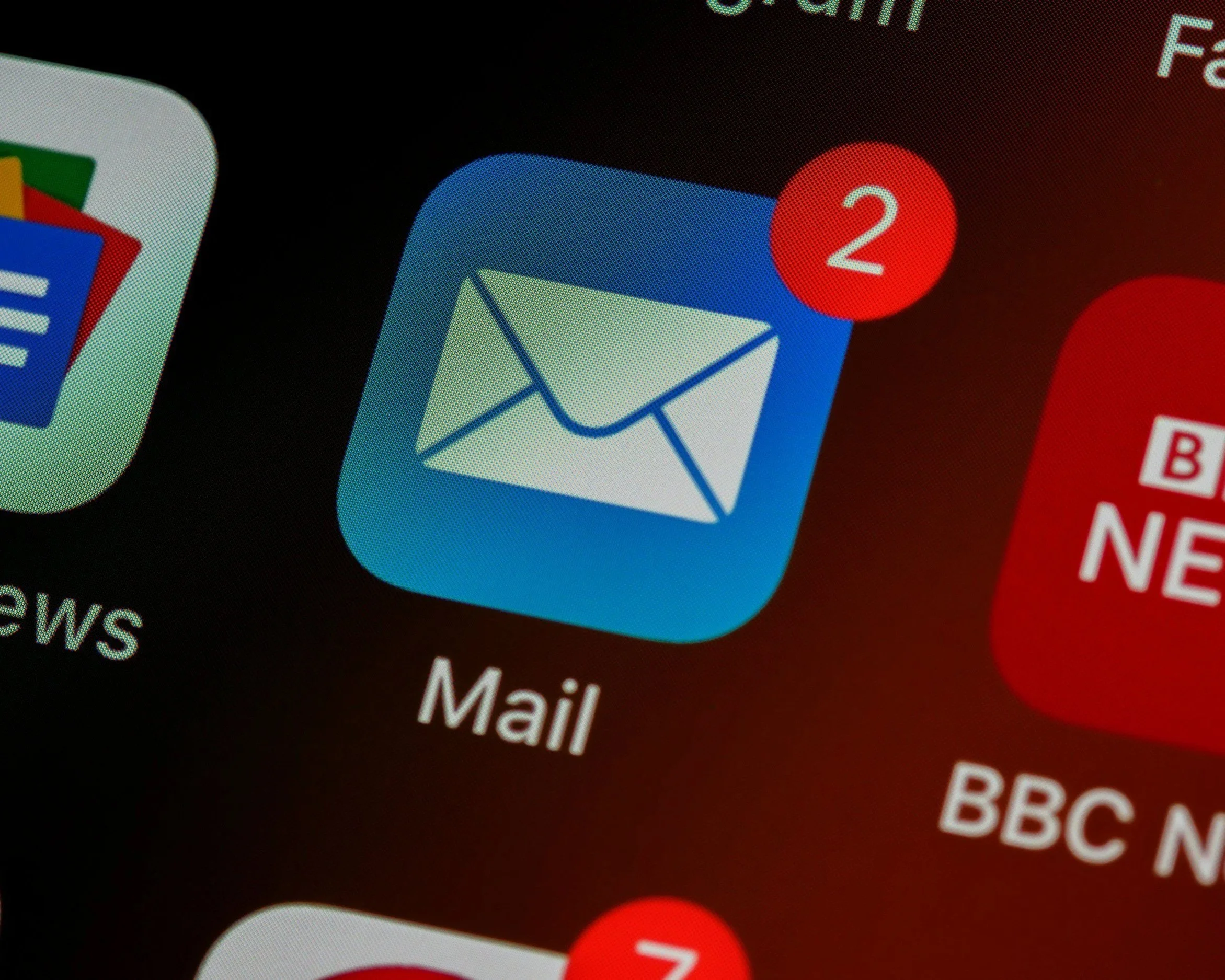 Close-up of an iPhone screen showing email app icons with notification badges, including one with two unread emails.