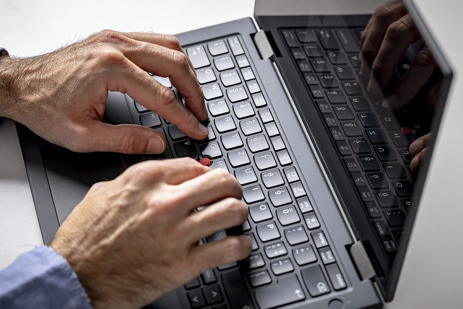 Nahaufnahme der Hände einer Person, die auf einer Laptop-Tastatur tippt.