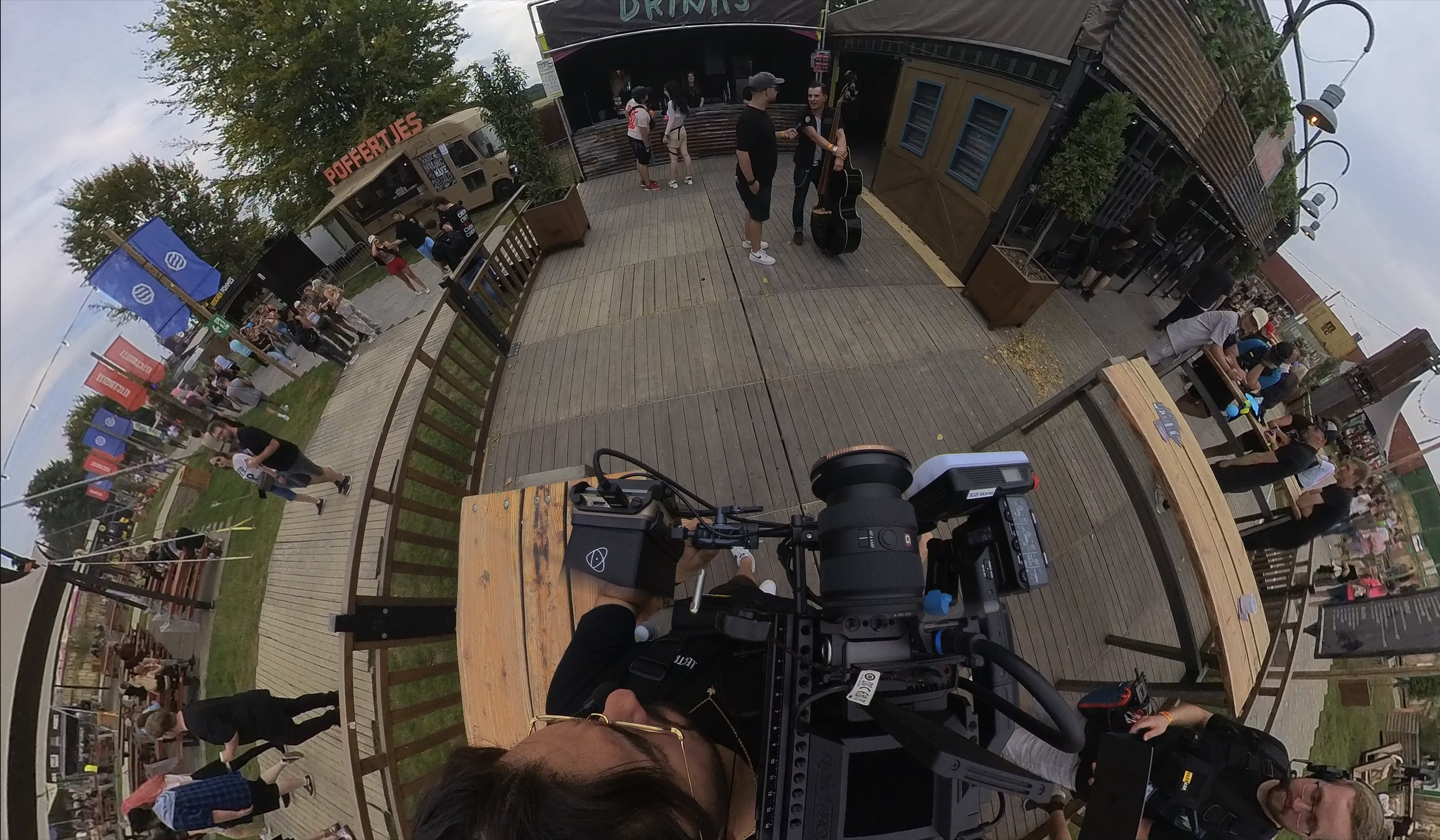 Aufnahmen im Freizeitpark mit einer Kamera aus der Vogelperspektive, inklusiv mehreren Menschen, Essensständen und Aktivitäten im Freien.