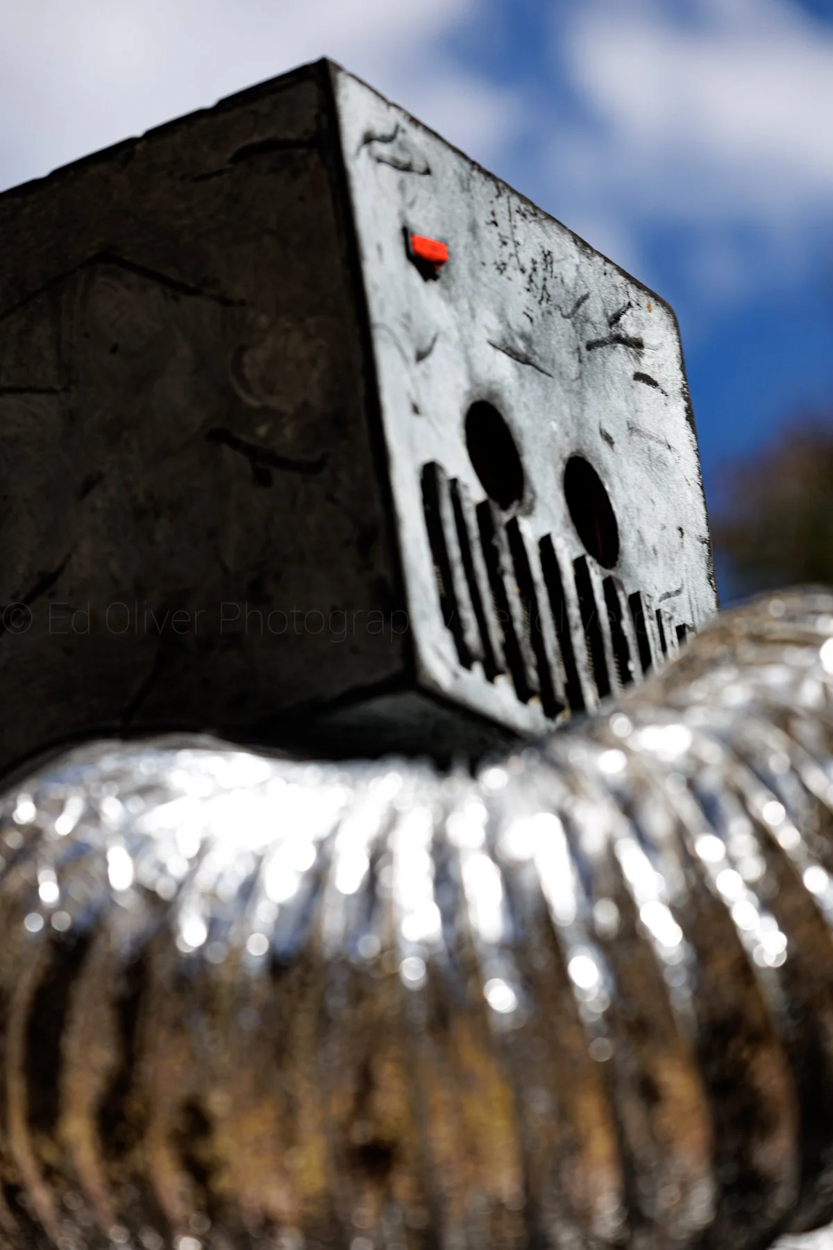 Close-up of a robot costume with a cloudy sky in the background.