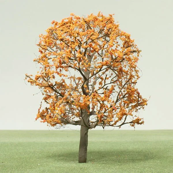 A model tree with orange leaves standing in an open grassy field against a pale sky.