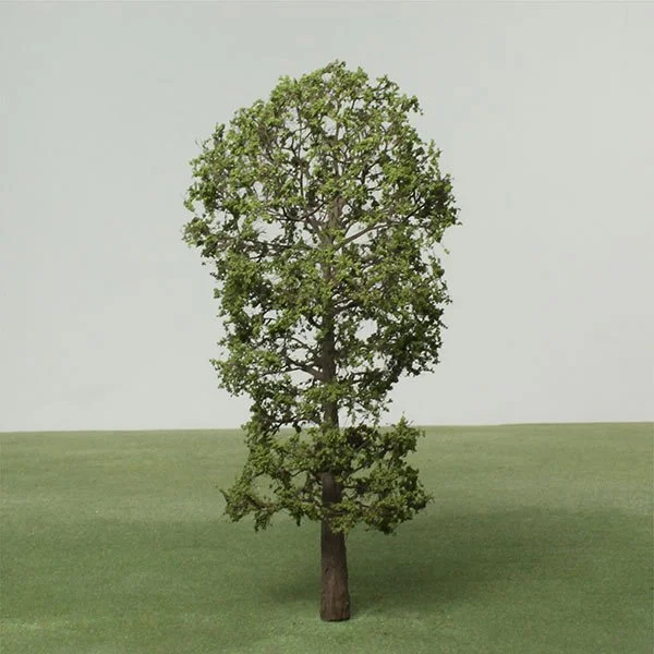 A single tall model tree with a full canopy of green leaves standing on a grassy field.