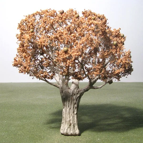 Small model tree with orange foliage and round yellow fruits on a green grassy surface.
