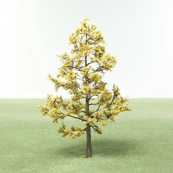 Small model tree with yellow leaves on green grass against a plain white background.