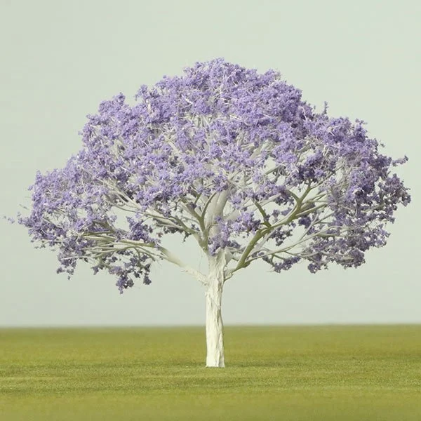 A model tree with purple foliage in an open grassy field against a plain sky background.