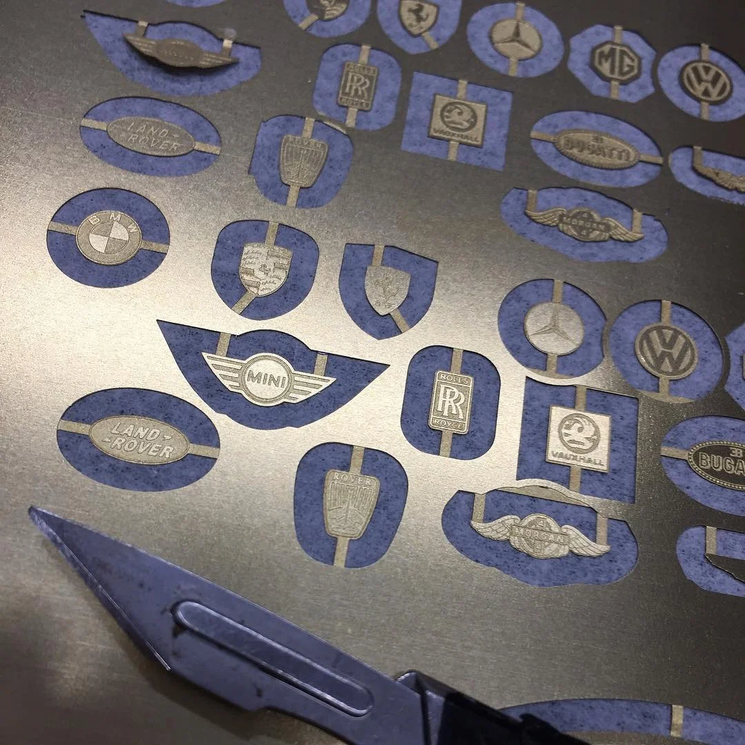 A series of model car emblems etched into nickel silver, tabbed into the sheet and ready to use. 