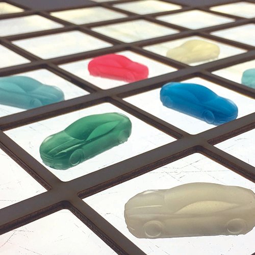 A set of clear cast tinted model cars on a lightbox
