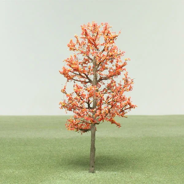 A model tree with pink and orange leaves standing on a grassy field under a light gray sky.