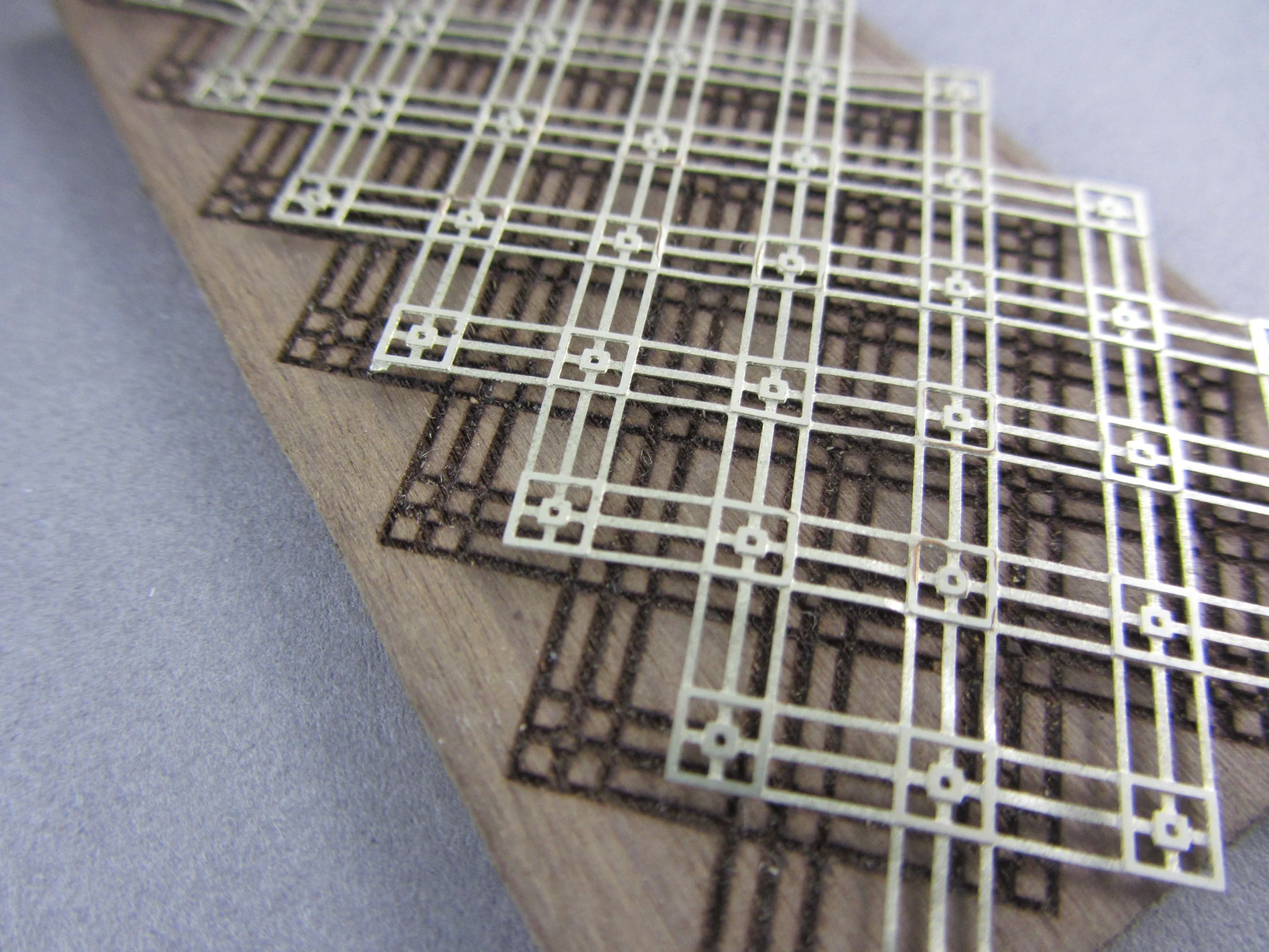 geometric artwork etched into nickel silver for inlay into laser engraved walnut wood.