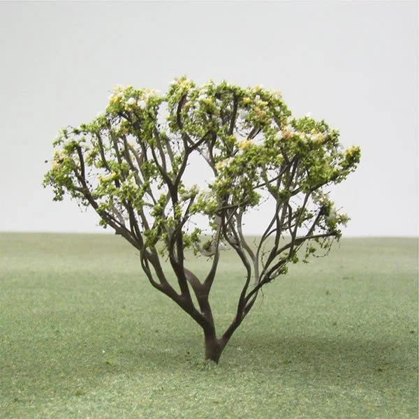 A small model tree with multiple branches spreading upwards, located on a grassy surface with a plain background.
