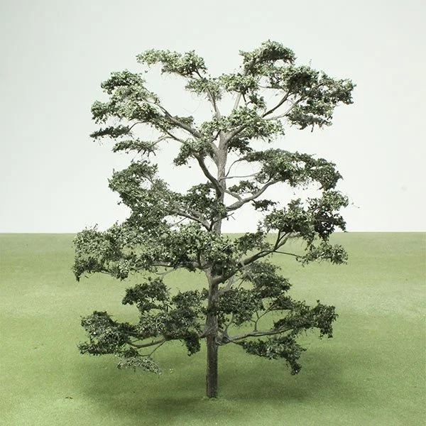 a Model Cedar of Lebanon tree with a straight trunk and arranged branches, on a plain green surface with a light background.