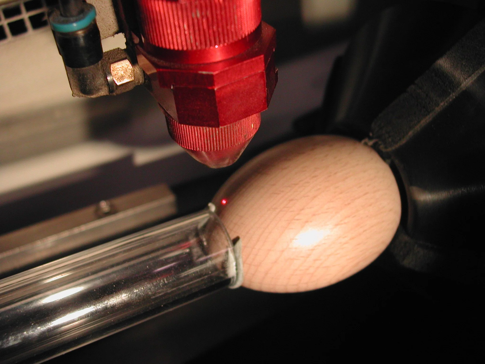 an image of a wooden egg set into a laser cutter rotary tool, ready for engraving
