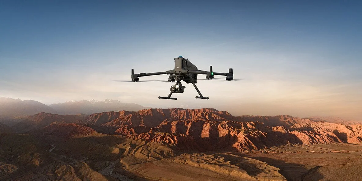 A drone flying over a mountainous landscape at sunset.
