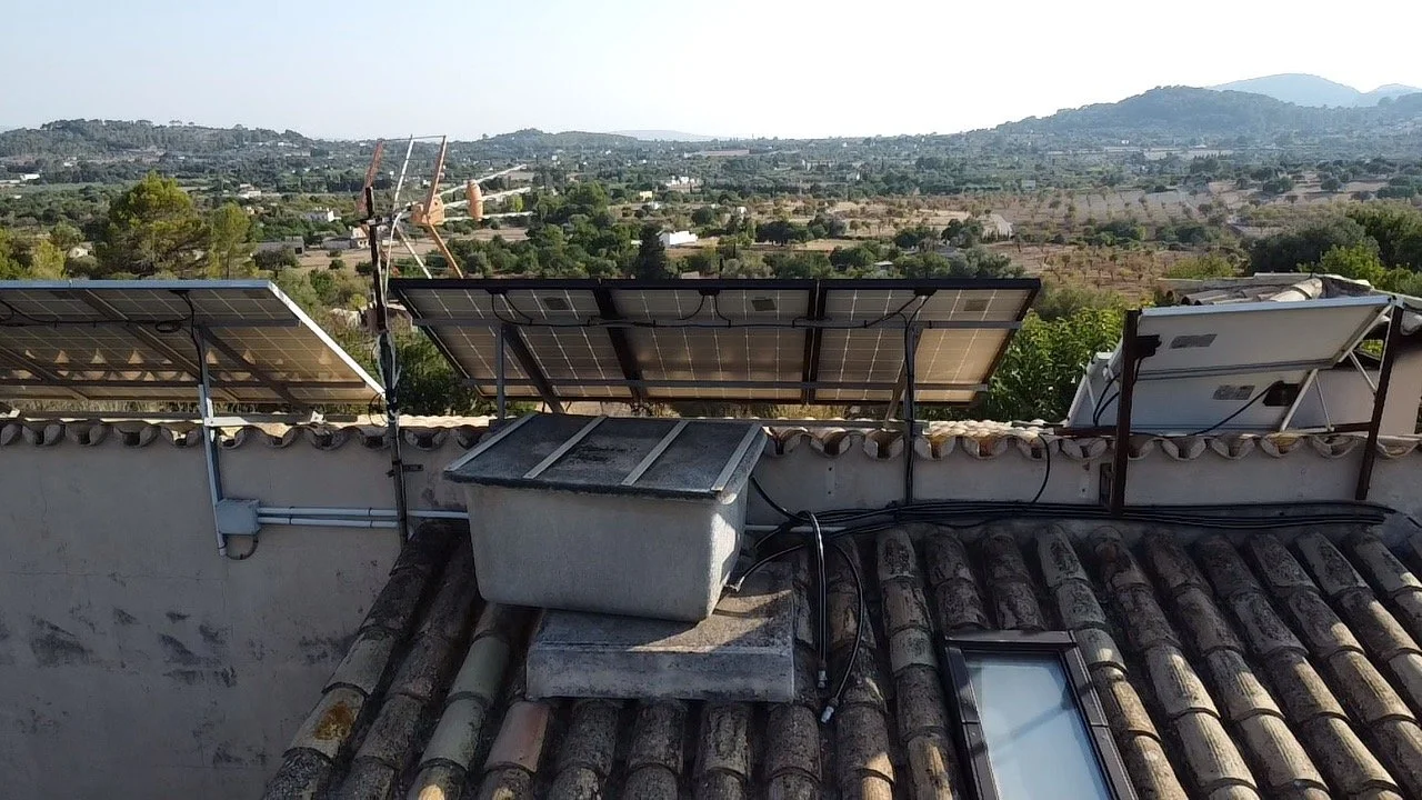 Solar panels installed on a rooftop with a view of a hilly landscape in the background.