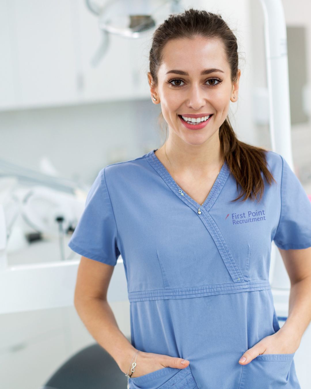 A smiling young woman wearing blue scrubs with