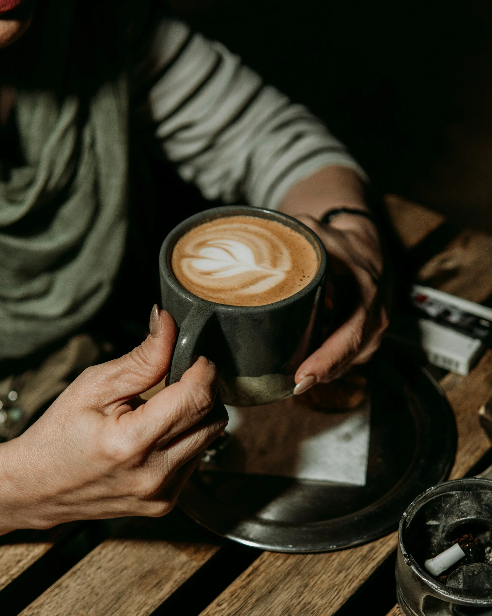 dark green cup of coffee held by someone in a green top