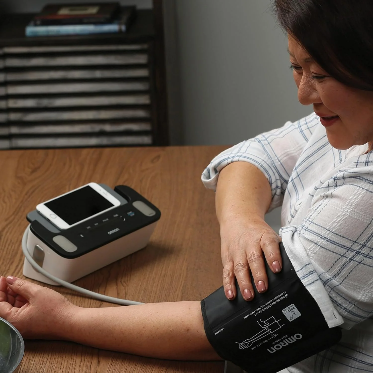 Omron Complete being used by a lady as she puts on the blood pressure cuff