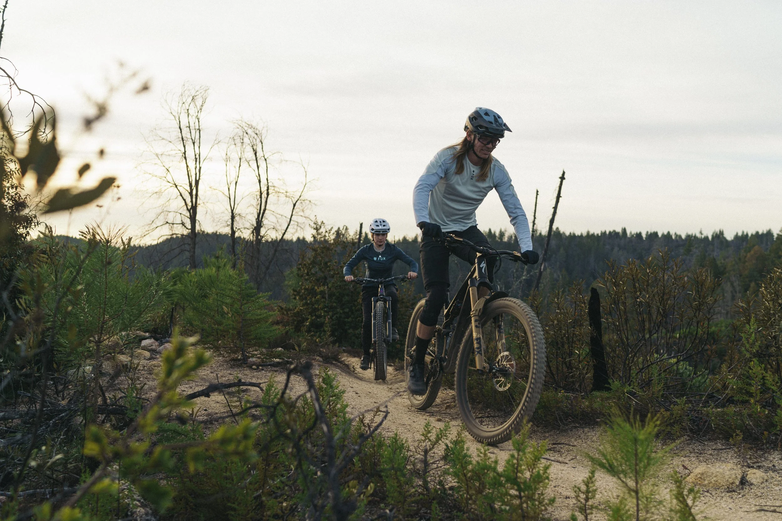 Deux cyclistes en VTT sillonnent un paysage sablonneux et végétal