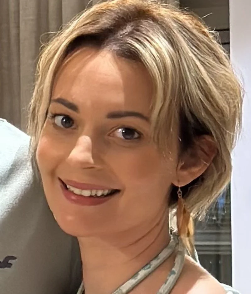 Close-up of a woman with short blonde hair smiling at the camera.