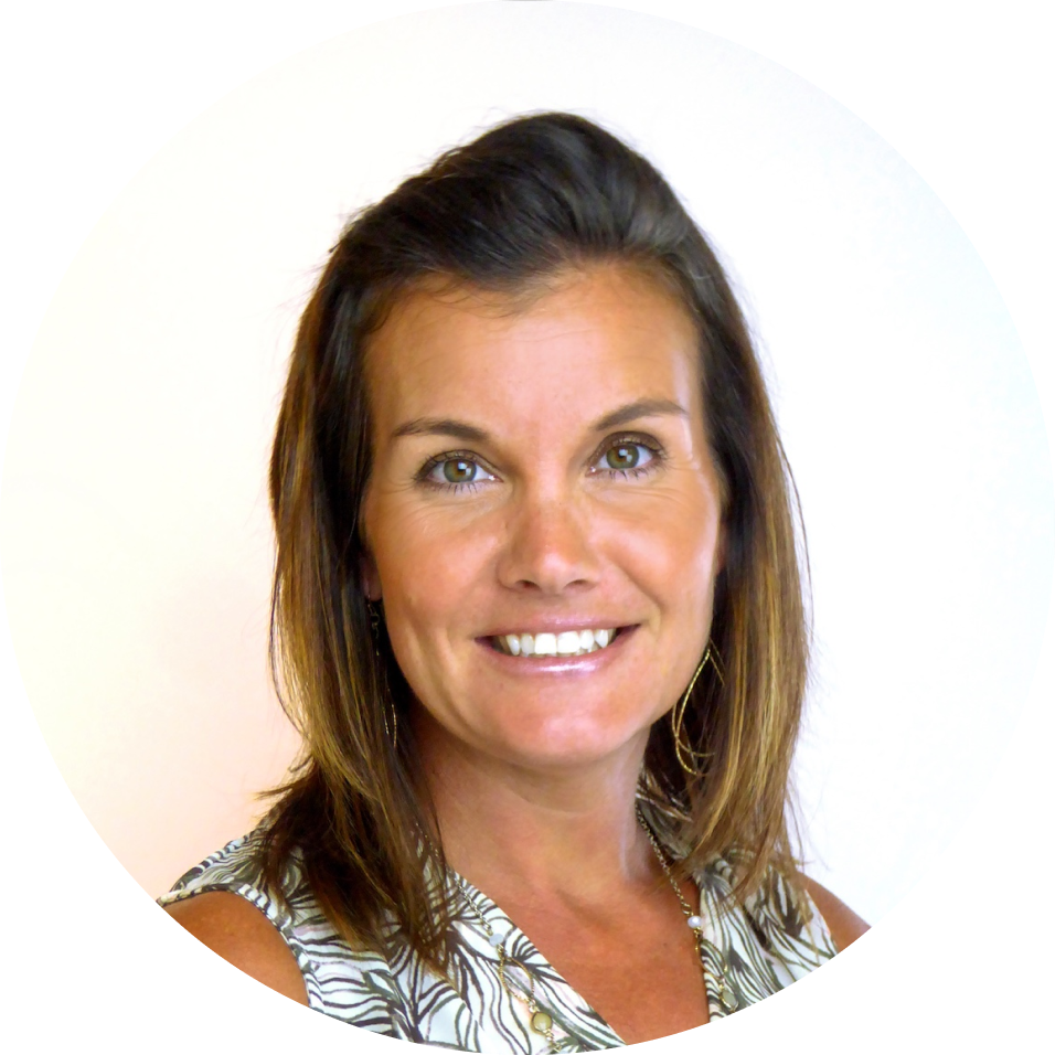 A woman smiling at the camera with shoulder-length brown hair, wearing a patterned top, against a plain white background.