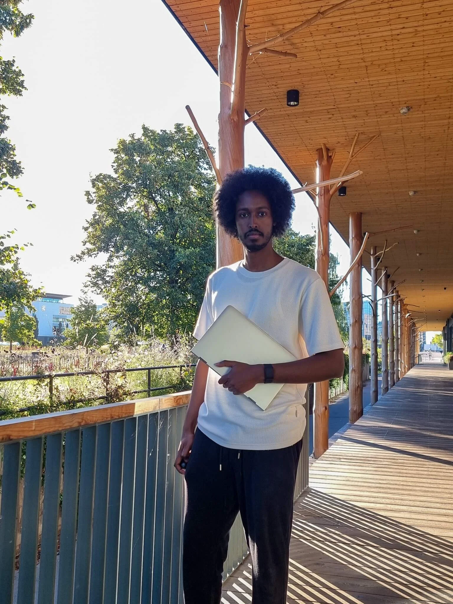 Image of studio owner and squarespace web designer Daahir Abdulle Standing Outside while holding a laptop