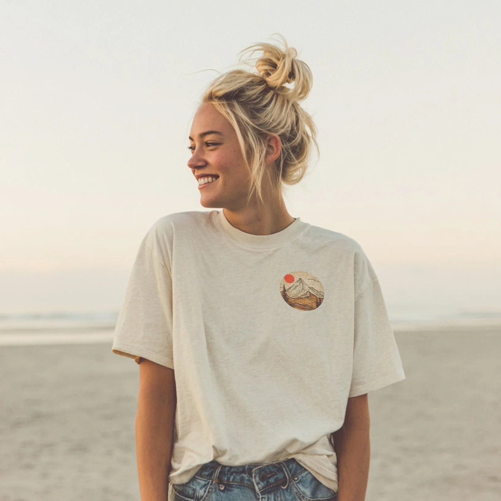 A blonde model wears a Christian t-shirt in Natural colour, with an image of a mountain and red sun, with the words 'Mountains can be moved'