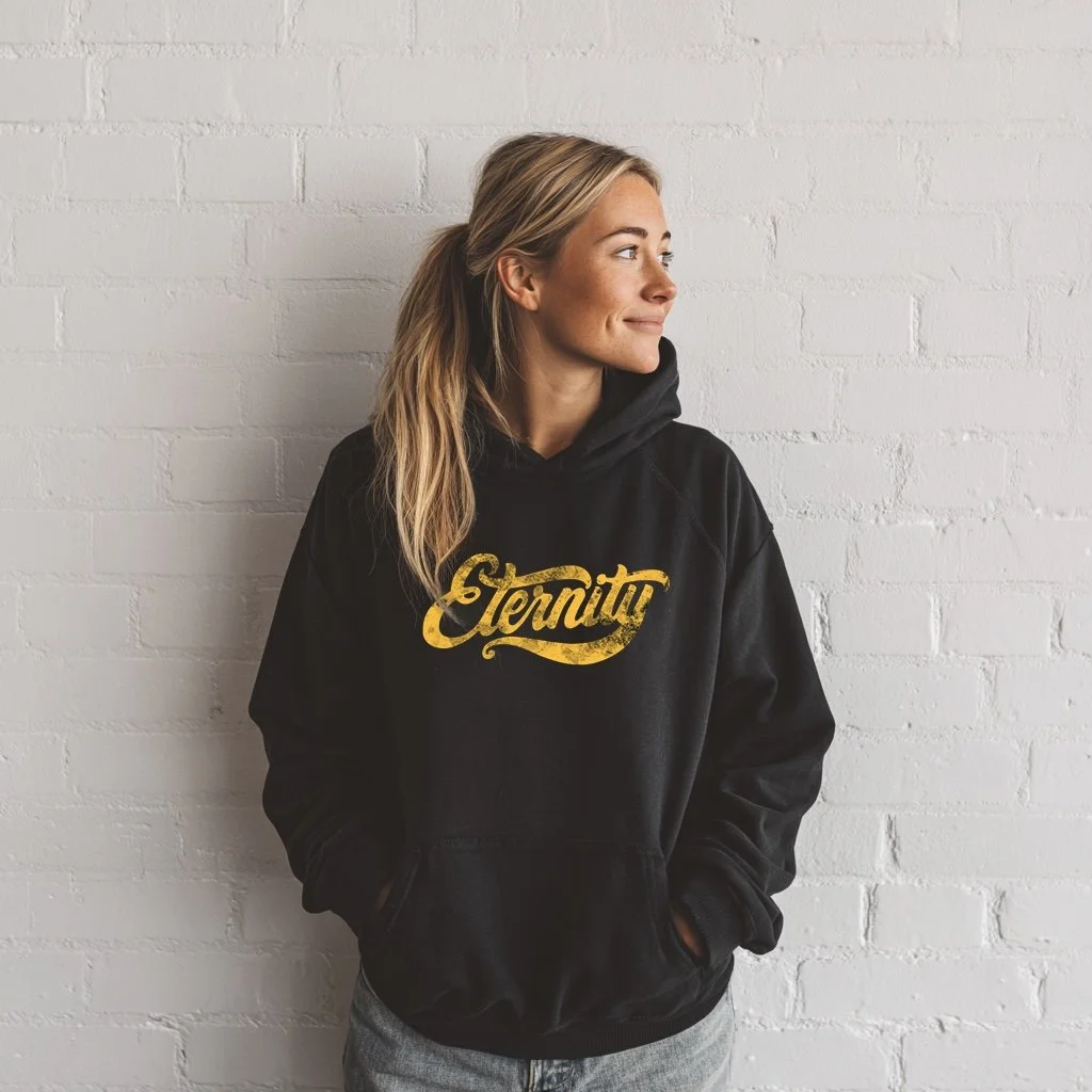 A blonde model wears a Black Christian Hoodie, with the word Eternity in yellow on the front, in beautiful script writing