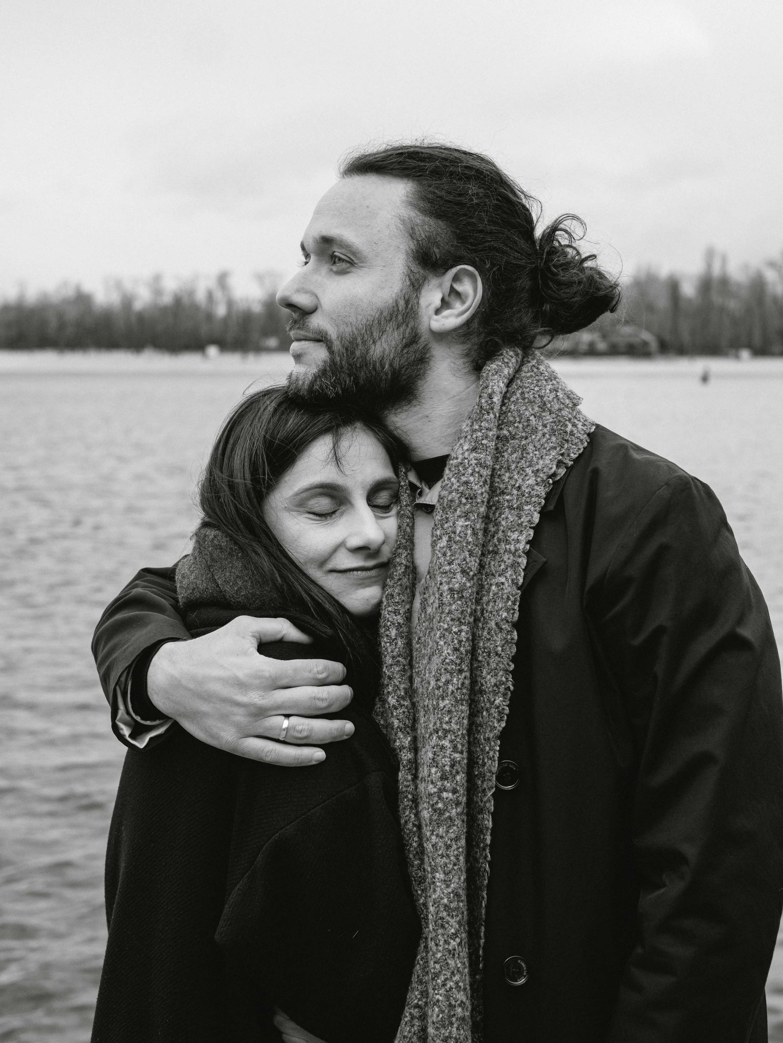 A couple hugging by the water.