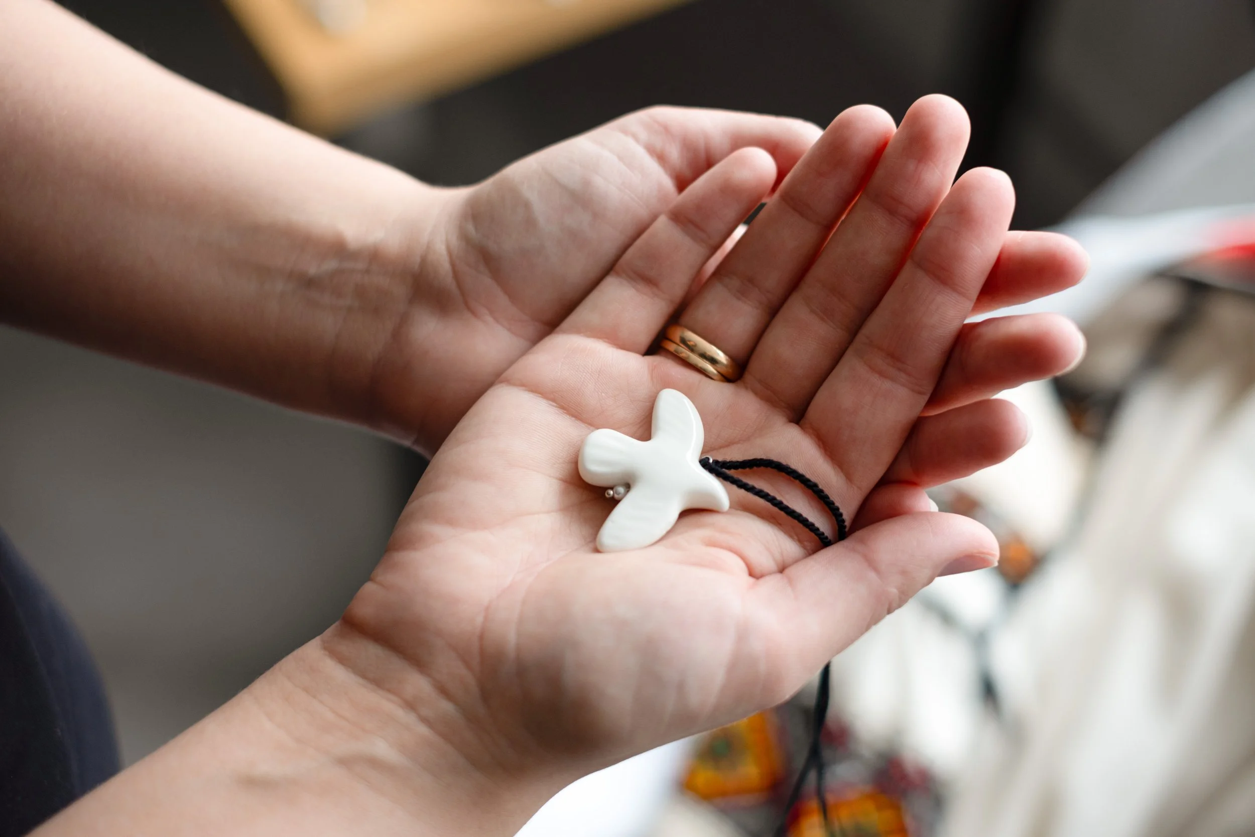 Hands holding a white pendant.