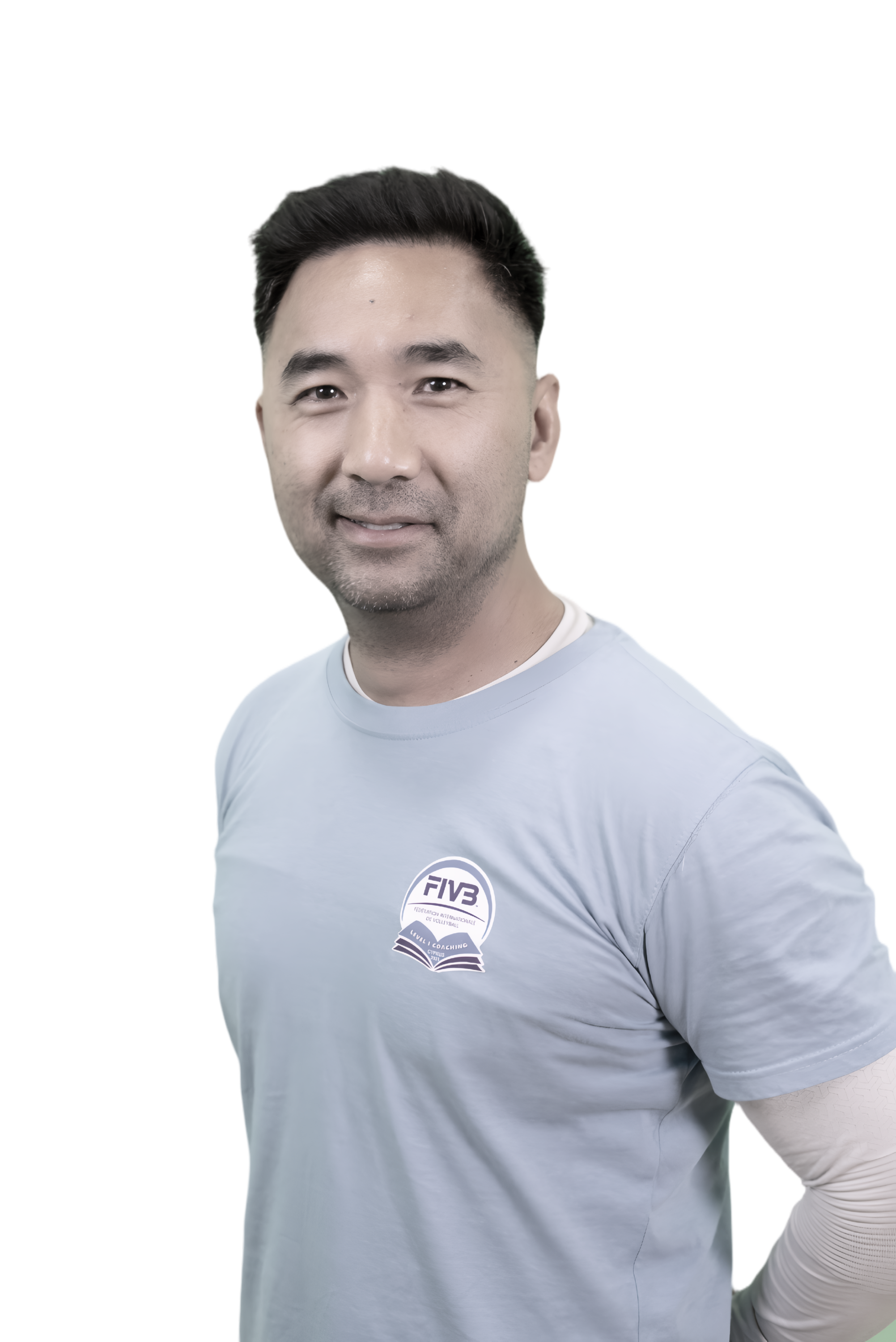 A man with short black hair and a light beard, smiling, wearing a light gray T-shirt with a volleyball logo on it.