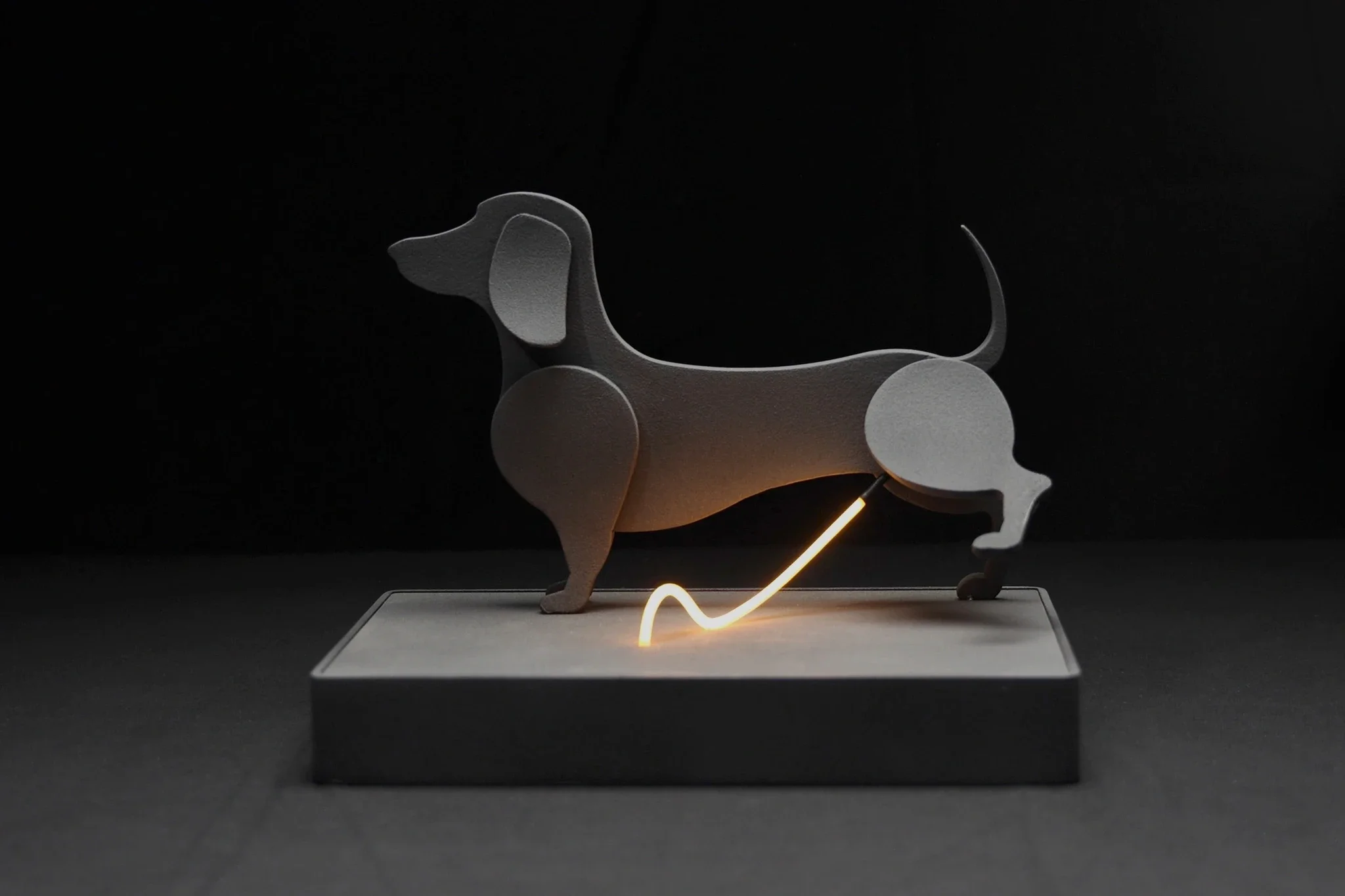 A decorative dog sculpture with illuminated upward arrow on a gray base, set against a black background.