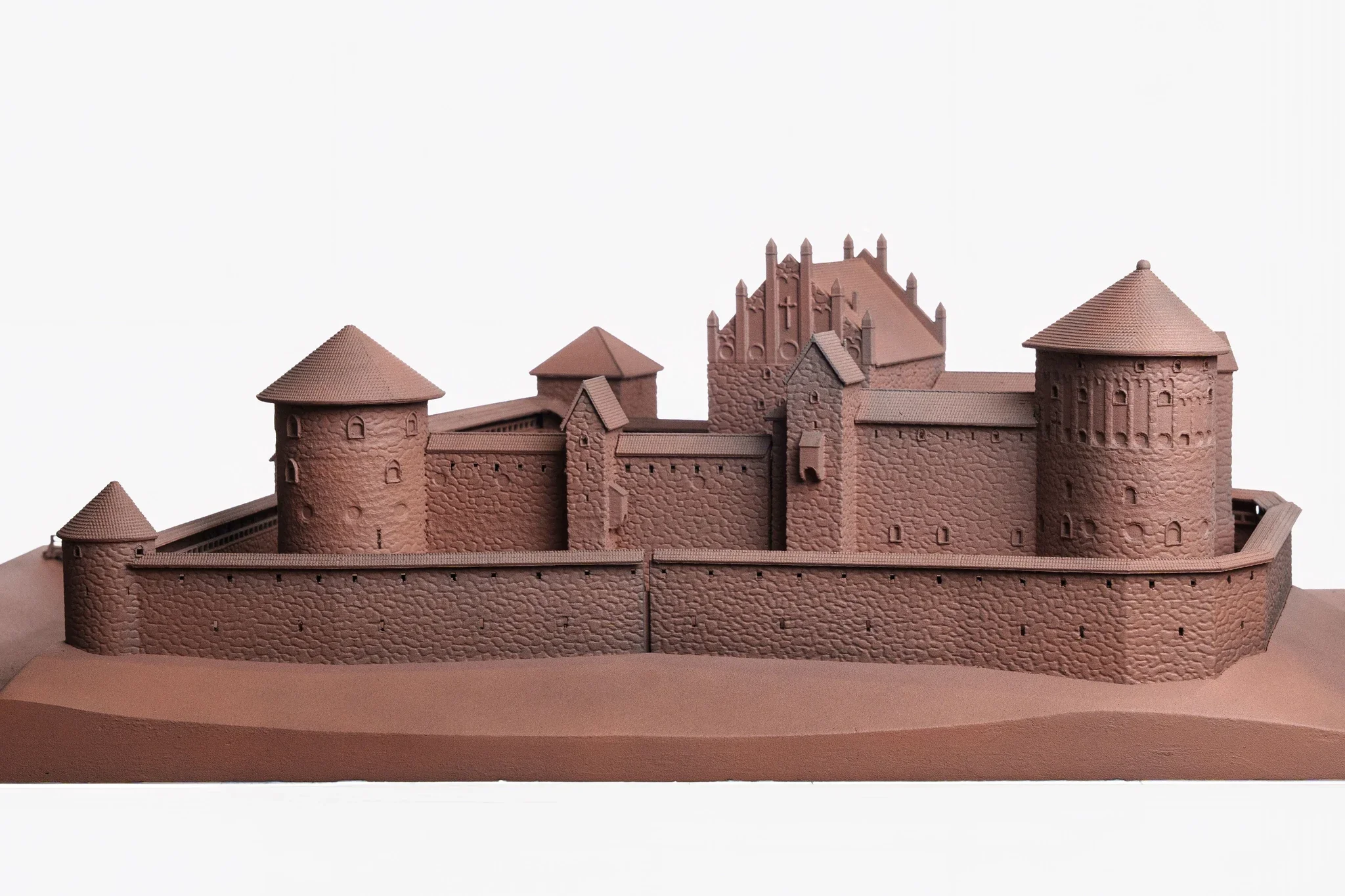 A detailed brown model of a medieval castle with towers, walls, and a central section, set against a plain white background.