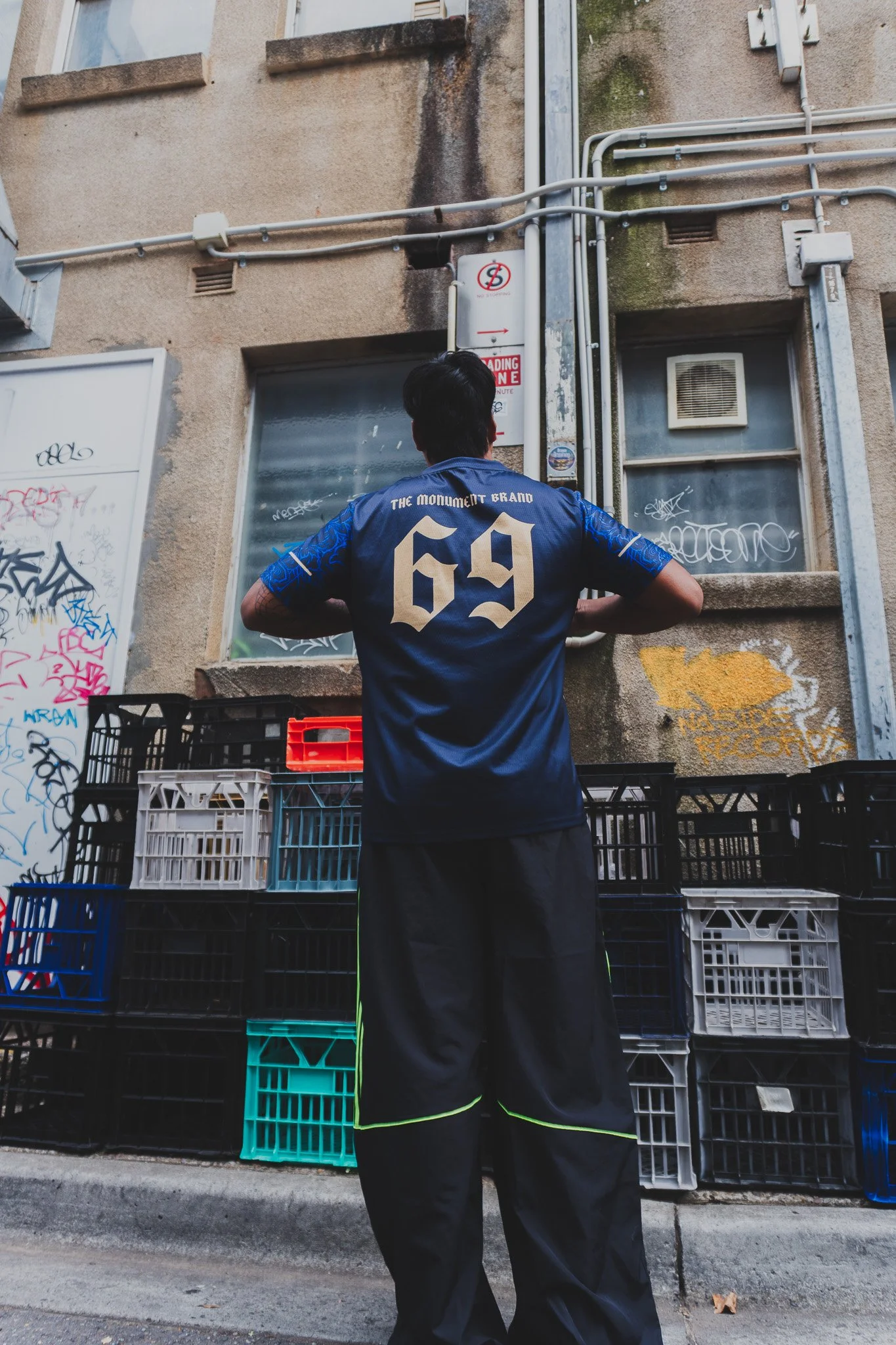 a person wearing dark blue gym tshirt with letters 69 printed on top and a dark grey parachute track pants