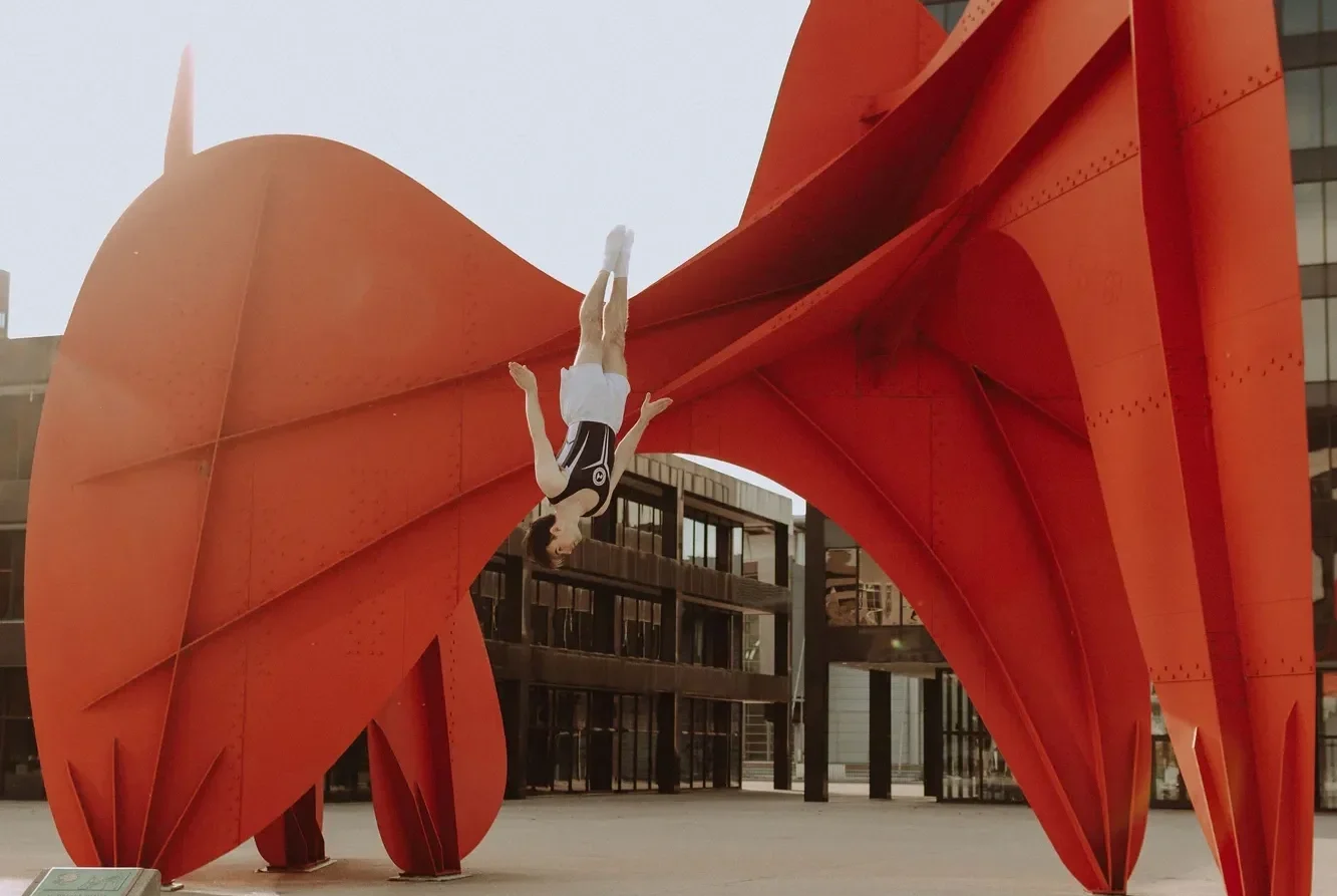 athlete flipping in front of Calder sculpture