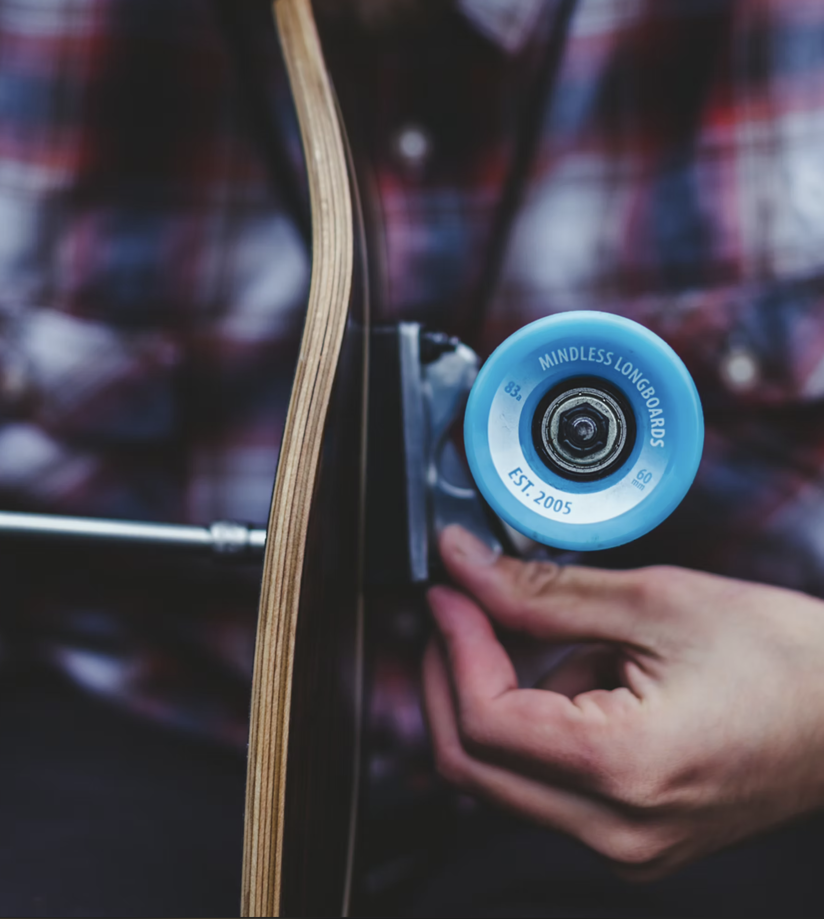 Close-up of a skateboard wheel labeled 'Mindless Longboards' being attached to a skateboard deck.