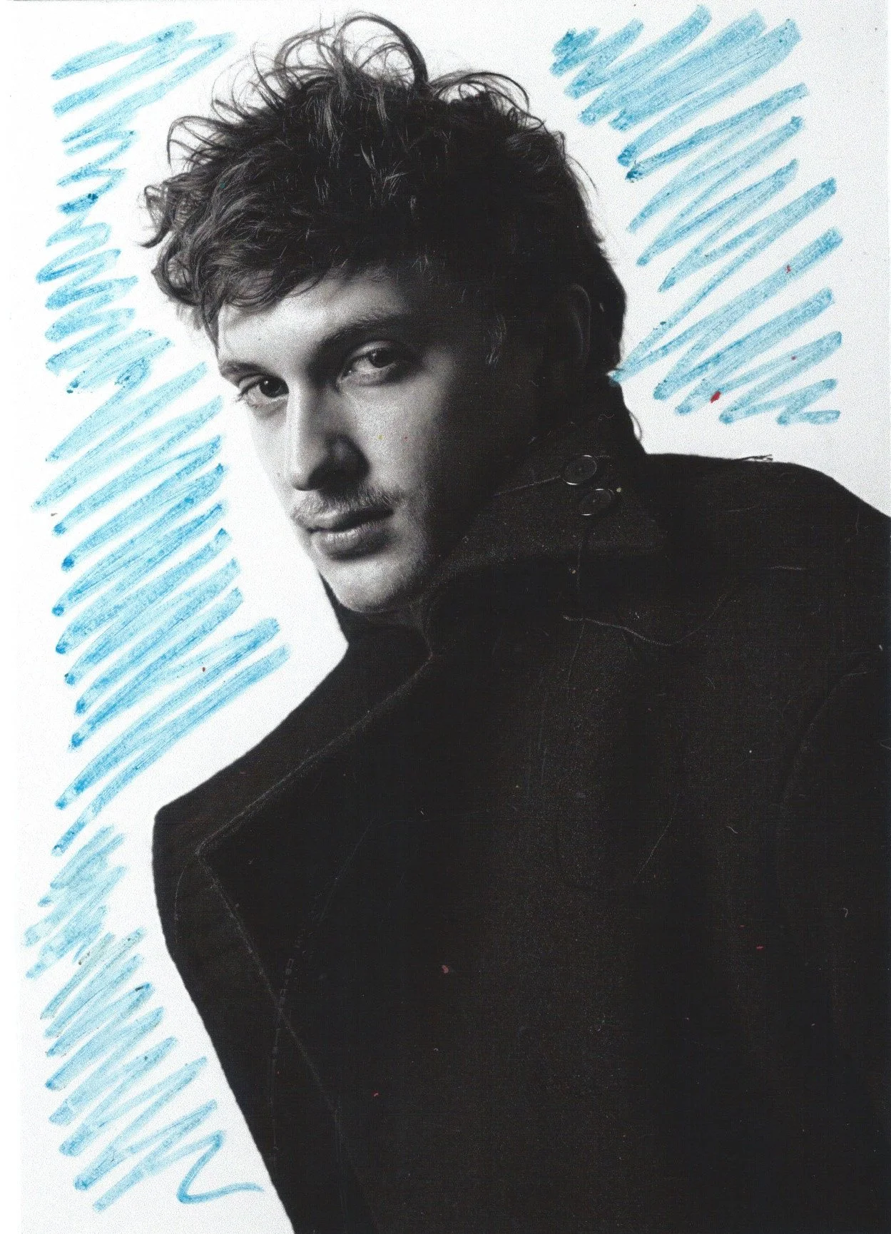 A black-and-white portrait of a young man with wavy hair, wearing a dark jacket, with light blue and dark blue scribbled lines in the background.