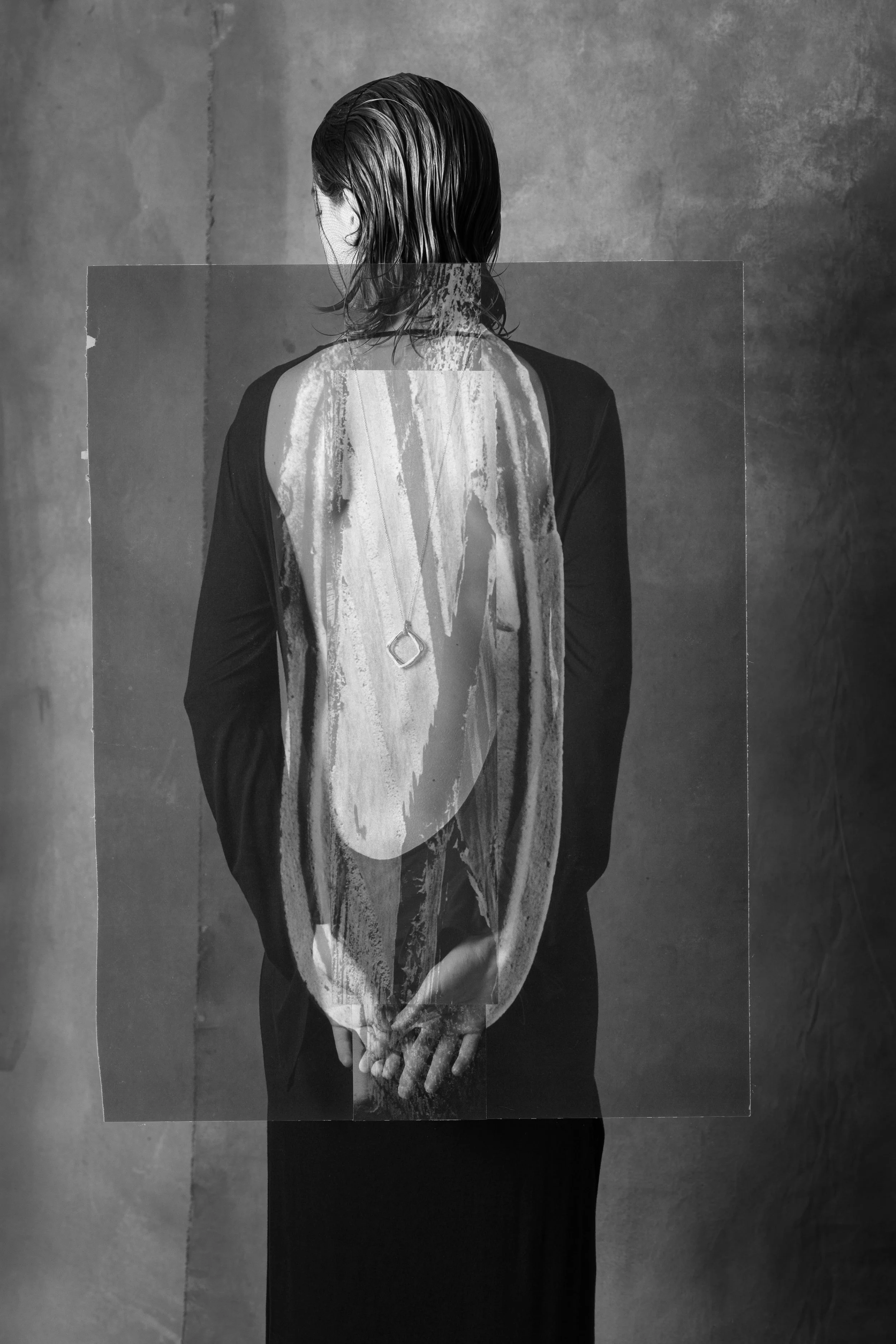 Black and white photo of a person with wet, slicked-back hair, wearing a dark long-sleeved shirt, standing against a textured background. There is a distorted, semi-transparent overlay of a person's back and hands over the image.