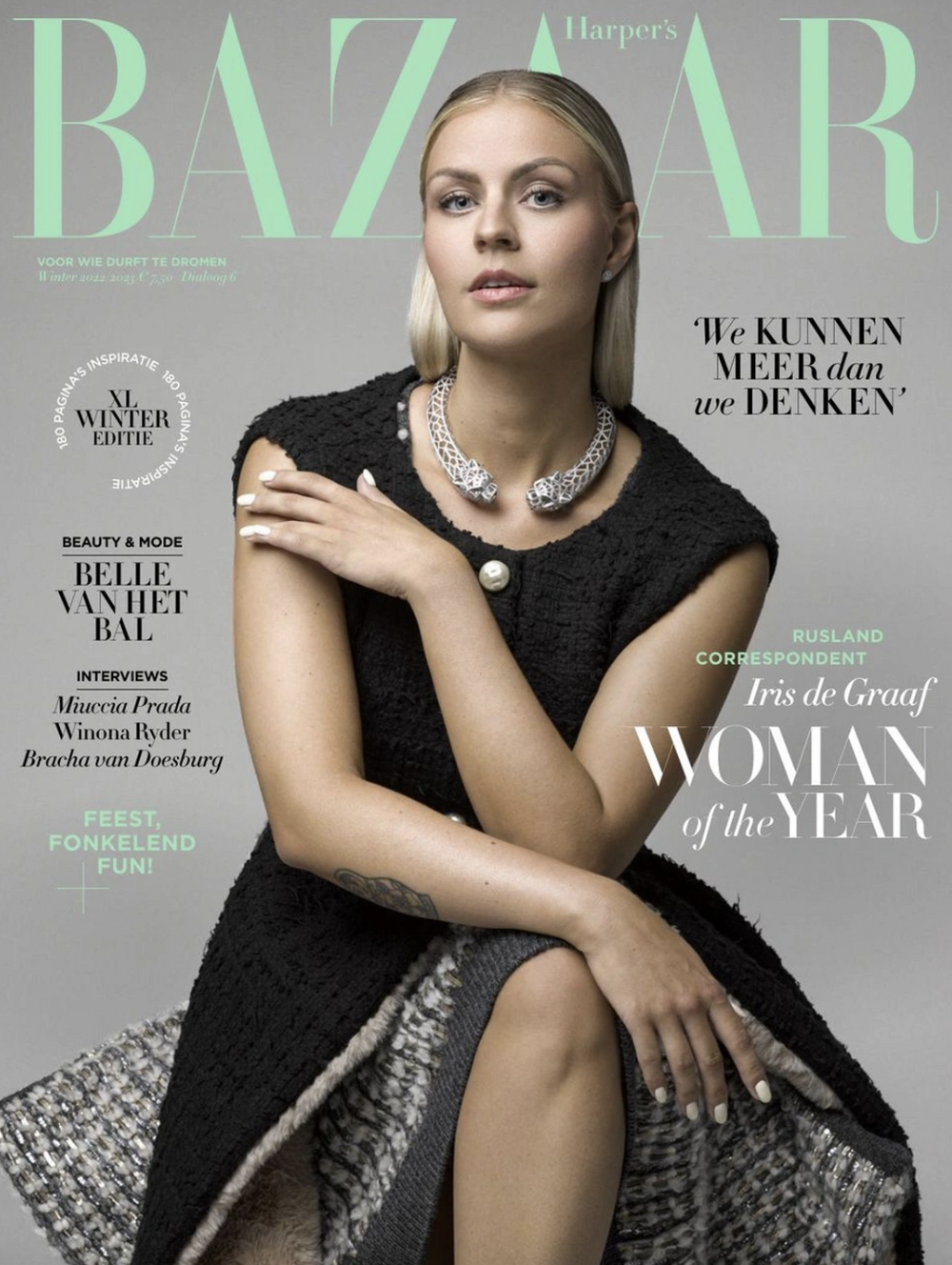 Cover of Harper's Bazaar magazine featuring a woman with blonde hair wearing a black textured dress and a statement necklace, sitting with her legs crossed and her left hand resting on her knee. Shot by Robin De Puy