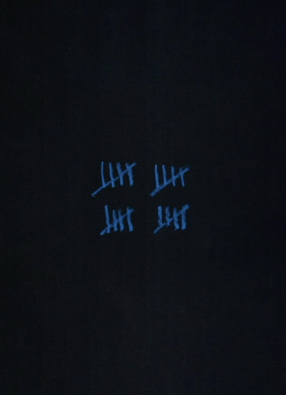 Four blue tally marks reflected on a dark surface.