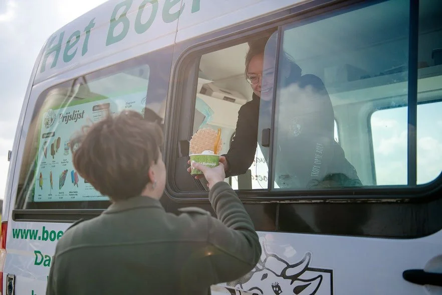 Man geeft een ijsje aan een vrouw in een ijswagen.