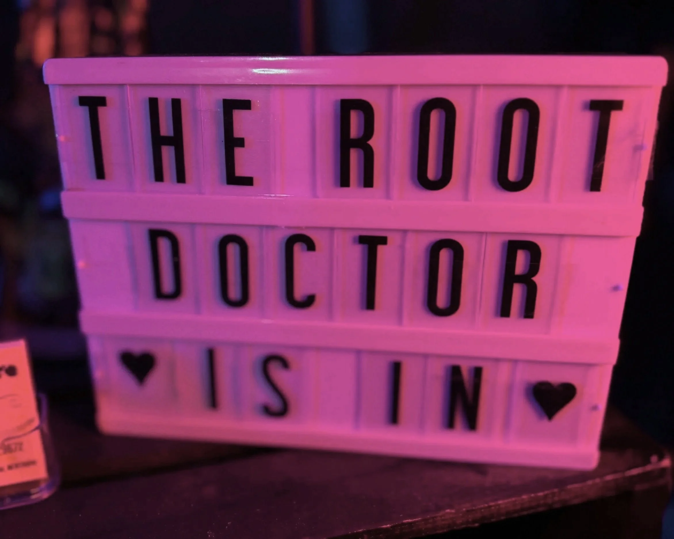 A pink box shaped like a film strip with the words "THE ROBOT DOLL" written on it in black capital letters.