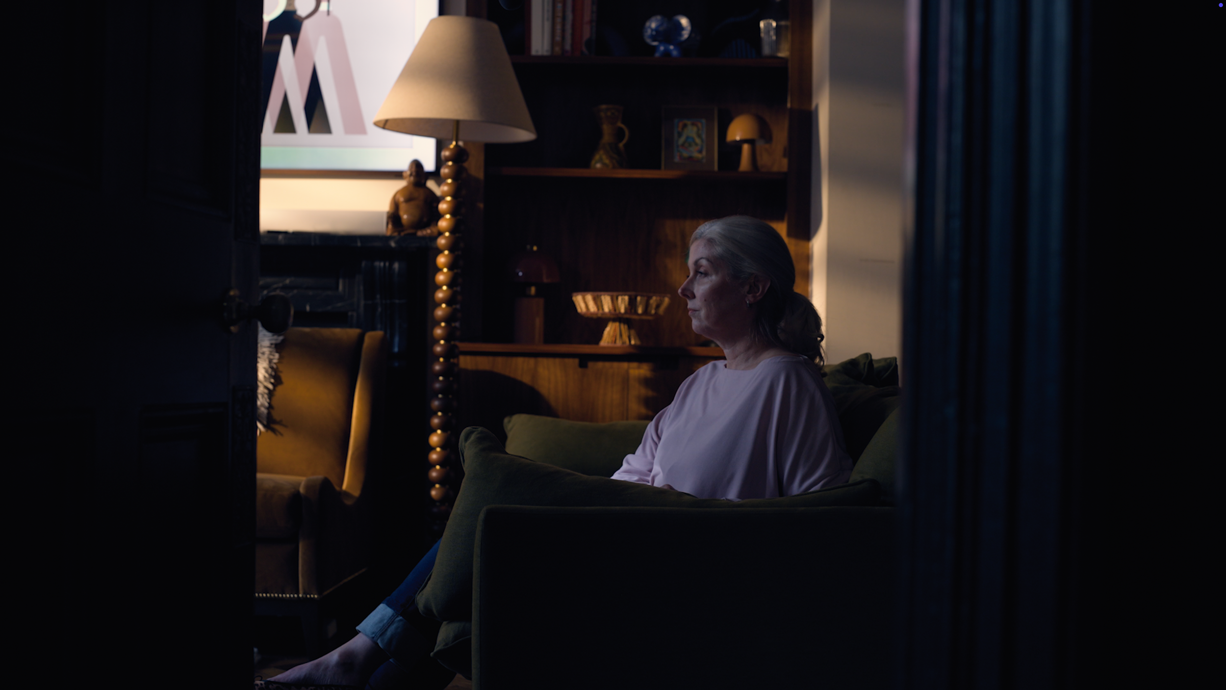 Cinematic production still of a female actor seated in a warmly lit study, filmed for a character trailer for a bestselling fiction title produced by Gunpowder House Productions for a UK publisher