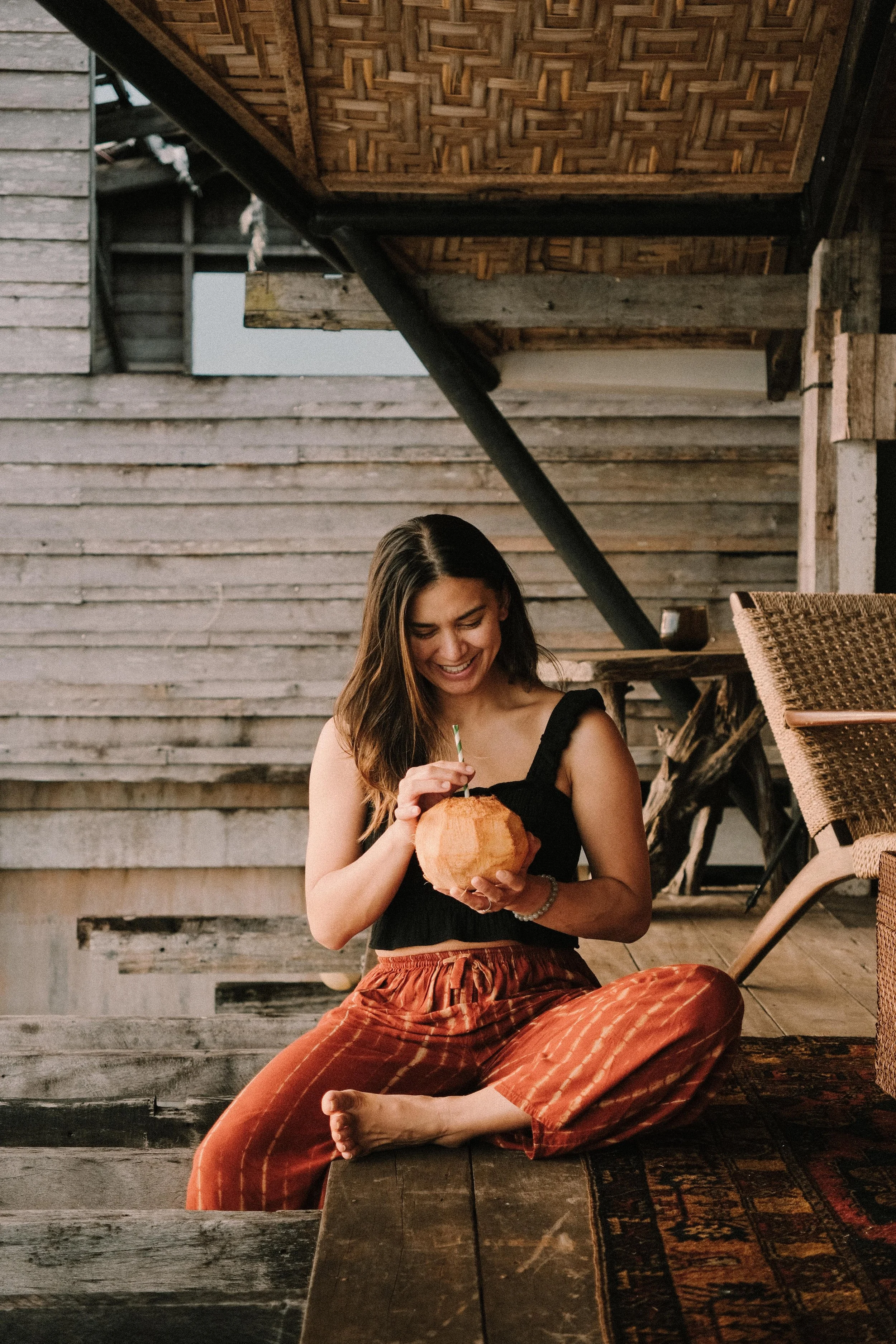Four women walking through a garden path surrounded by lush greenery and a trellis overhead.