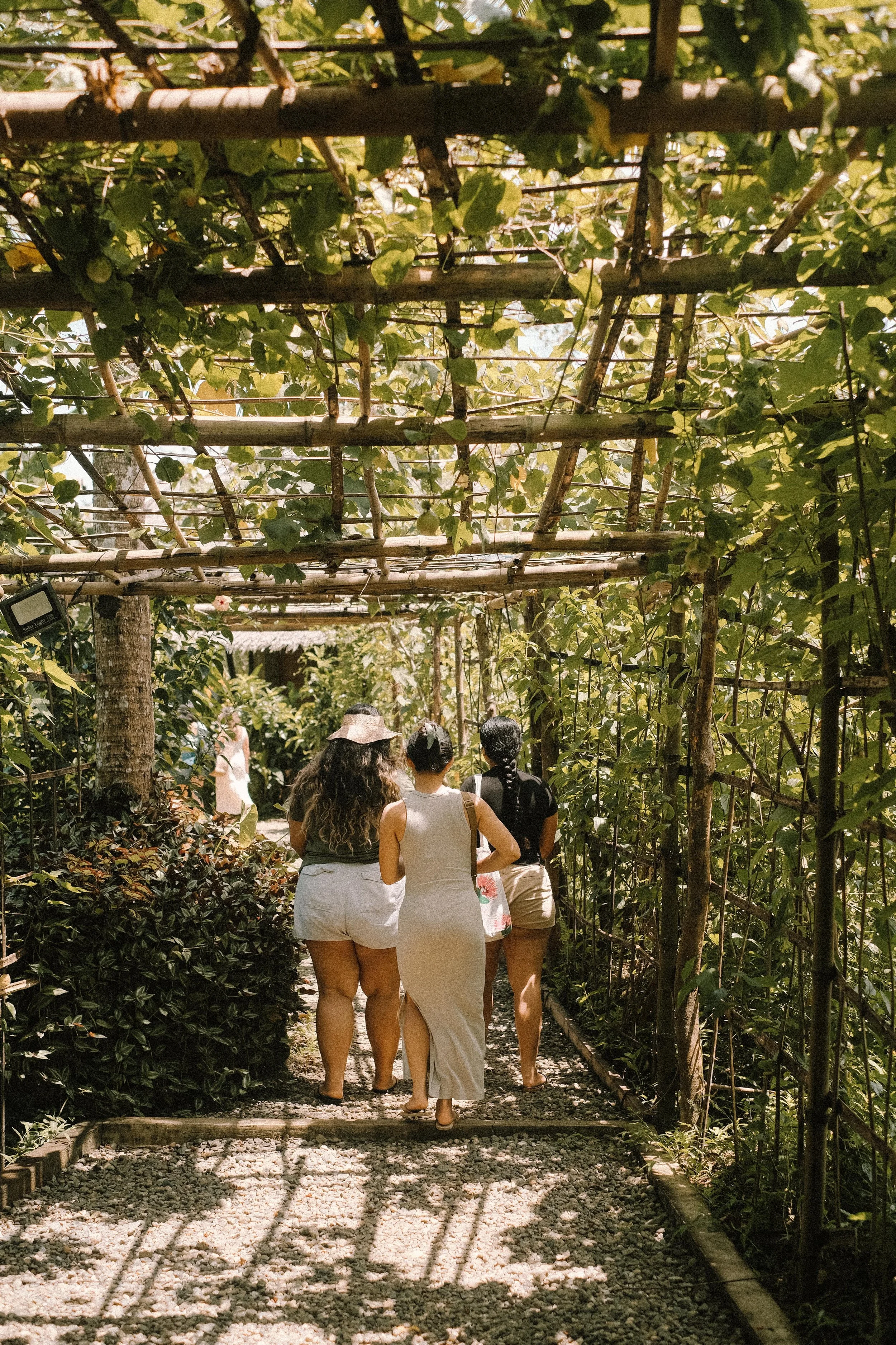 A person sitting on a dark mat writing in a notebook, with a tote bag labeled 'ina Bali Dinner Compass Retreat' on the floor nearby.