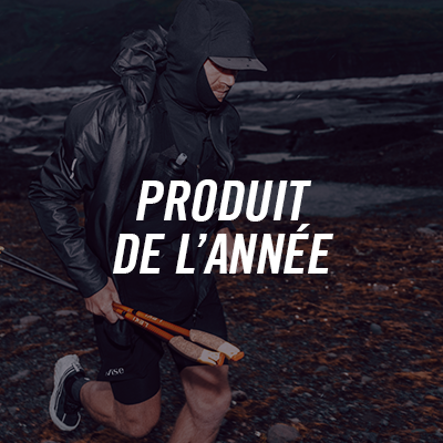 A man in a black jacket and hood, holding a wooden axe, running on a rocky beach at night, with the text "Produit de l'année" in French.