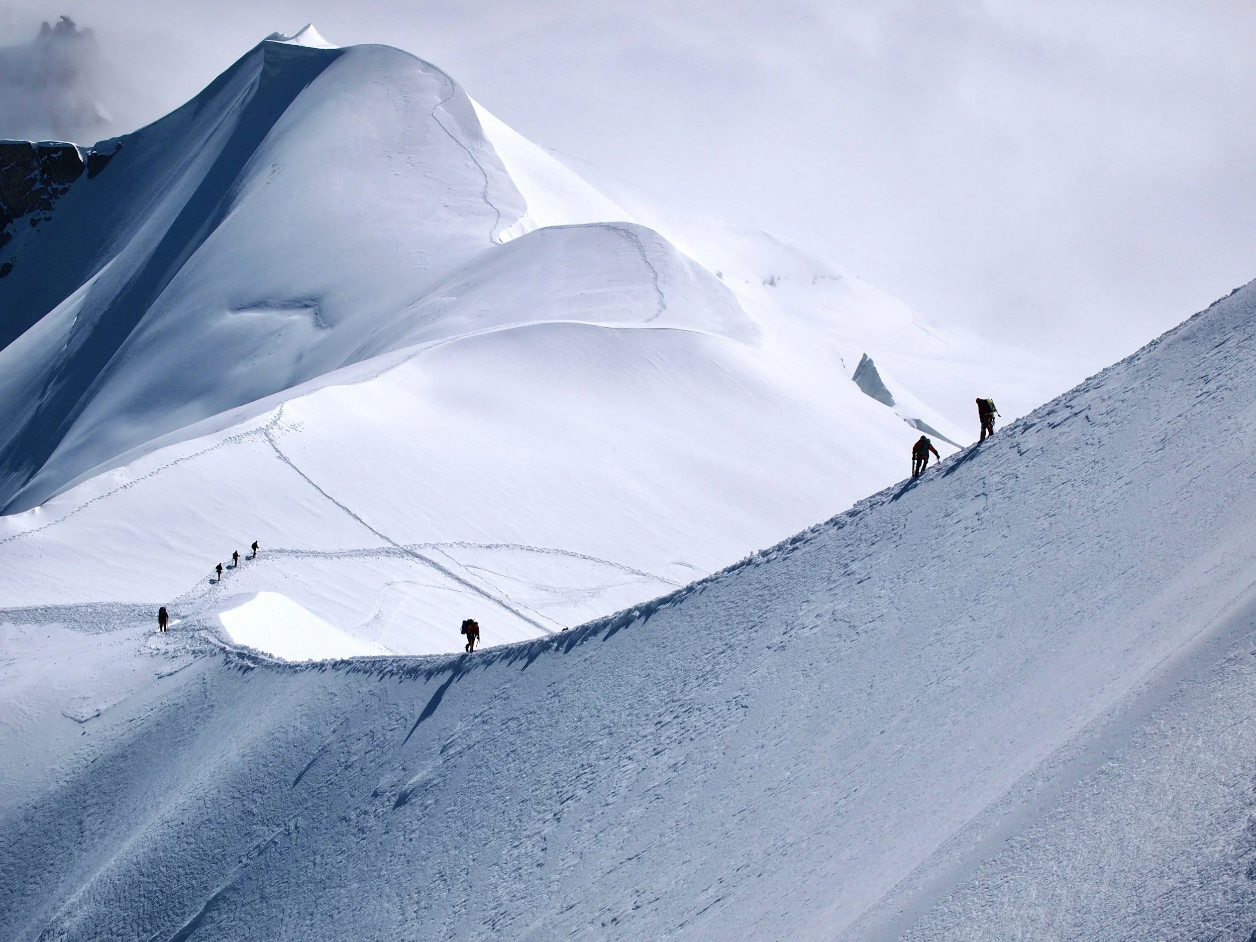 A group of mountaineers climbing a snow-covered slope on an icy mountain.