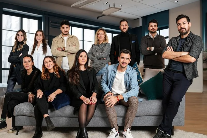 Group of 11 in a modern salon, posing for a team photo with a smile and confident posture.